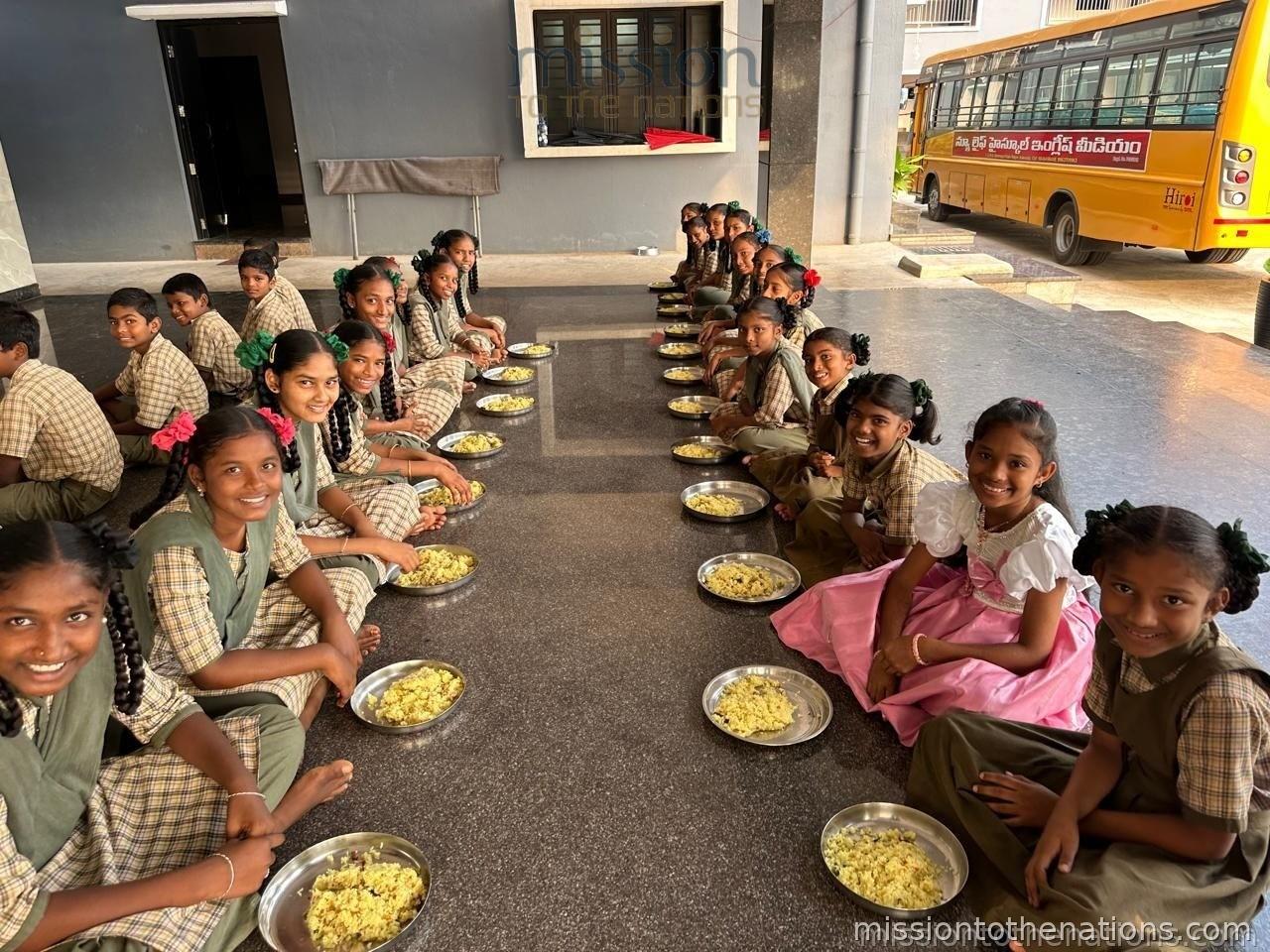 Children seated in rows receiving meals at school