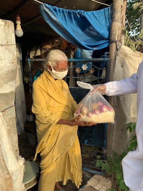 Old lady at her hut receiving groceries from COVID squad